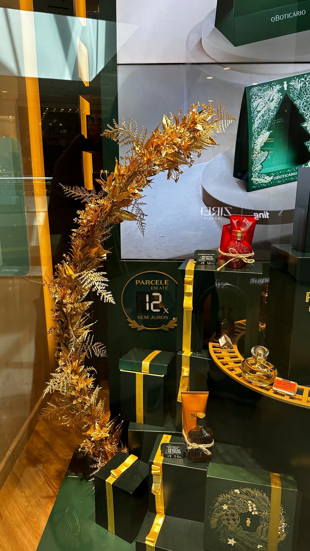 Guirlande de branches dorées dans la vitrine de Noël 2025 d'O Boticário