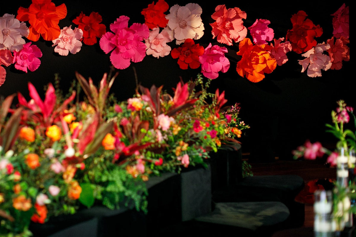 Mirrored dessert table framed by giant flowers in vibrant tones