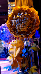 Giant flowers mounted on stems with green foliage - event floral installation