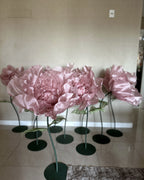 Large pink organza flowers on stands with green stems and leaves