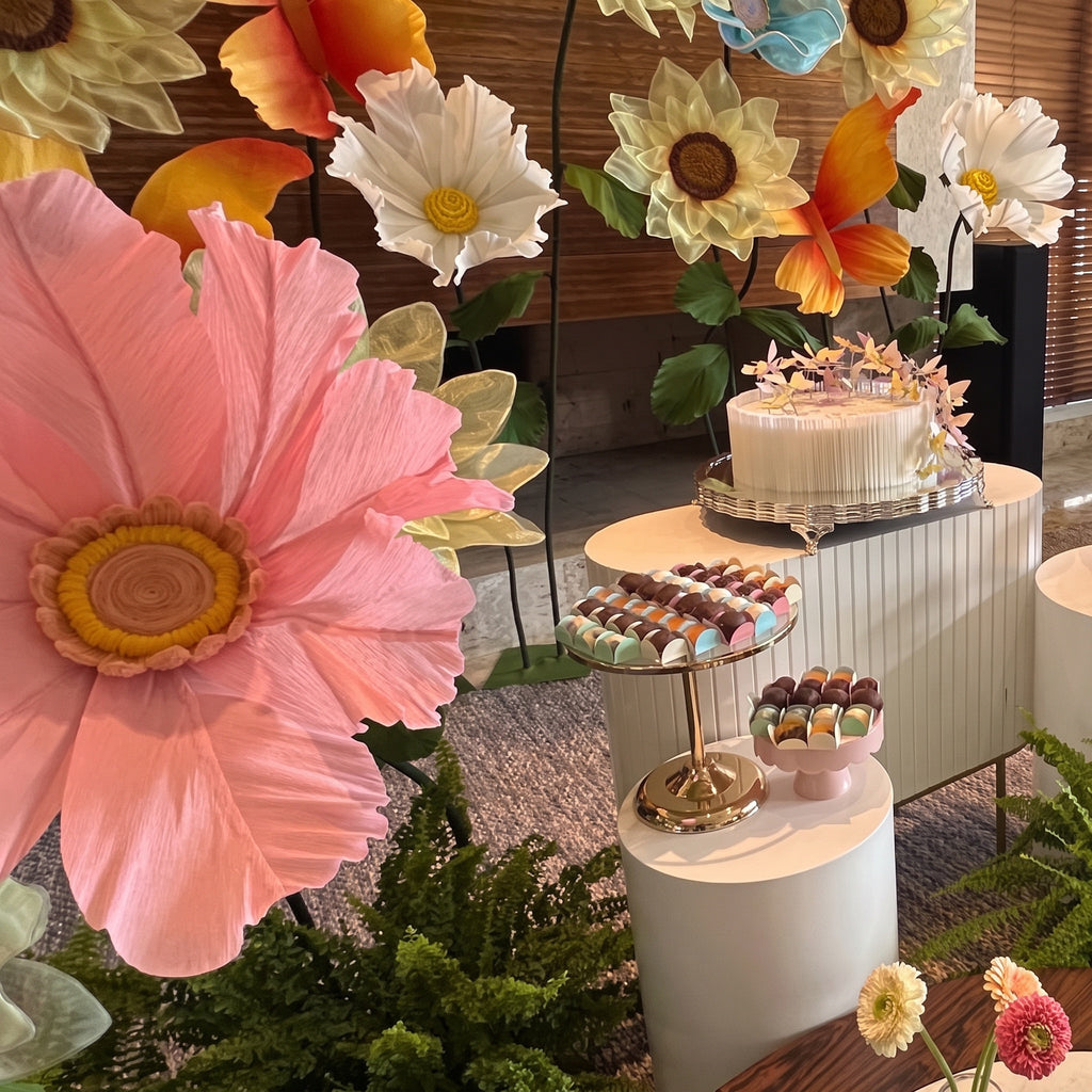 Flores gigantes de organza azuis, na mesa do bolo de um batizado