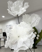 Flores gigantes de organza brancas pintadas à mão, mostrando a escala