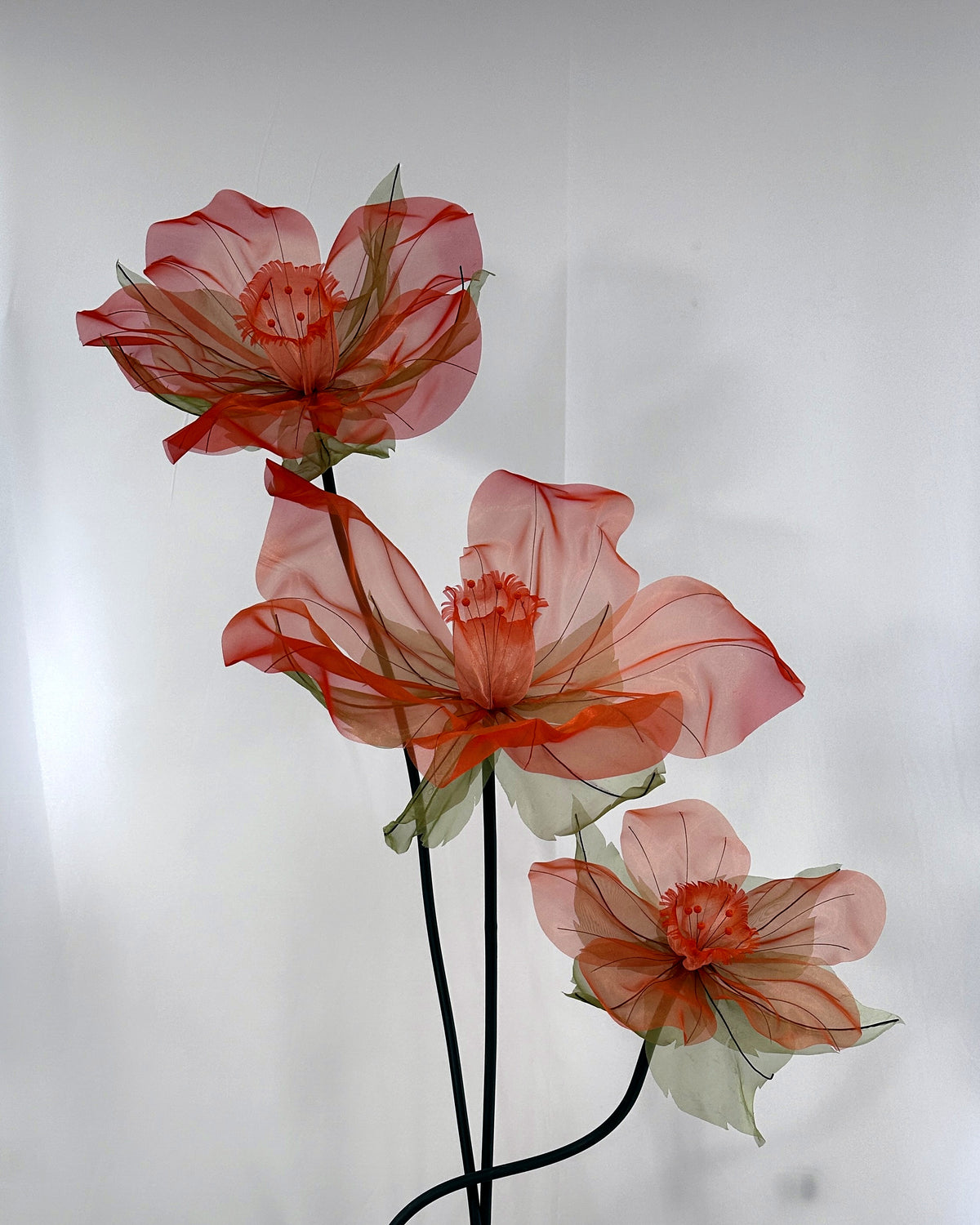 Pedestal com três narcisos gigantes de organza em degradê pêssego e coral