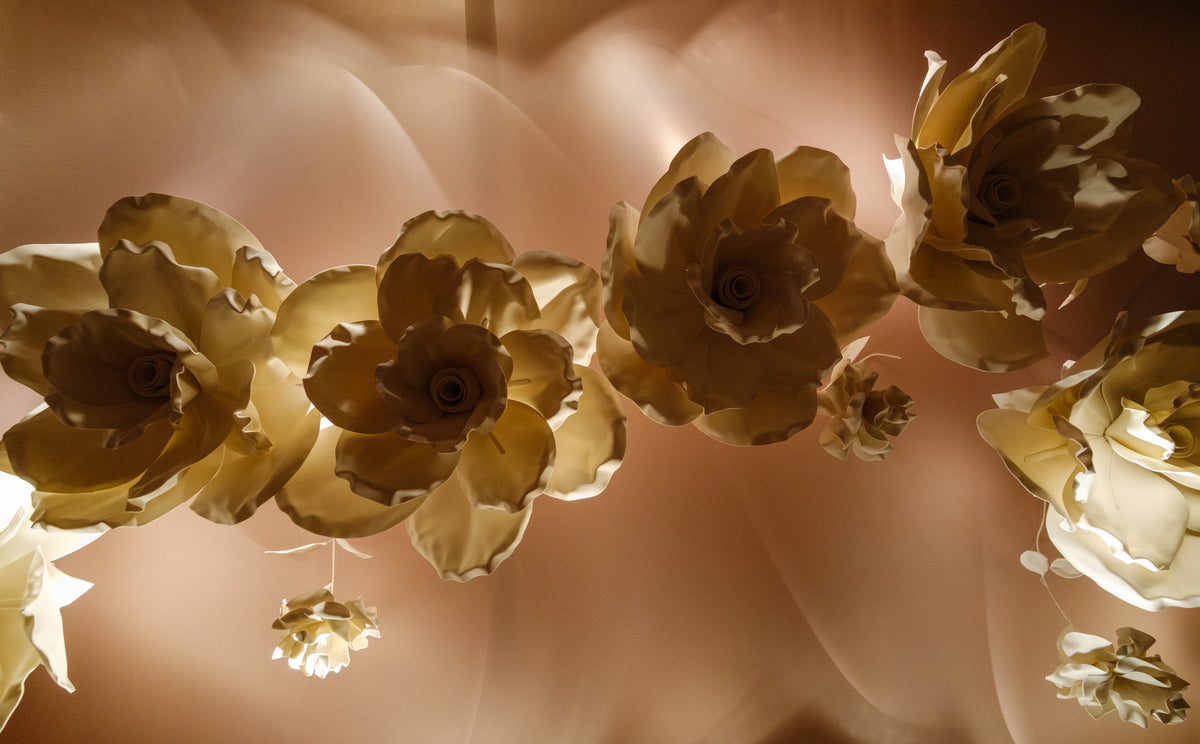 Close-up detail of layered giant flowers in gold tones — entrance corridor