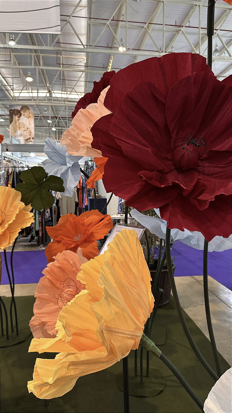 Visitantes fotografiando el stand decorado con flores gigantes