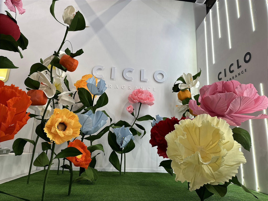 Composition finale du stand Ciclo Fragrance avec fleurs géantes