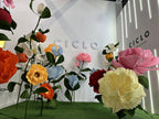 Composition finale du stand Ciclo Fragrance avec fleurs géantes
