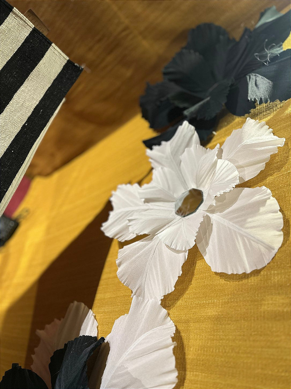 Composition of giant suspended flowers above the rugs on display