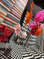 Pedestrians admiring the storefront decorated with suspended giant flowers