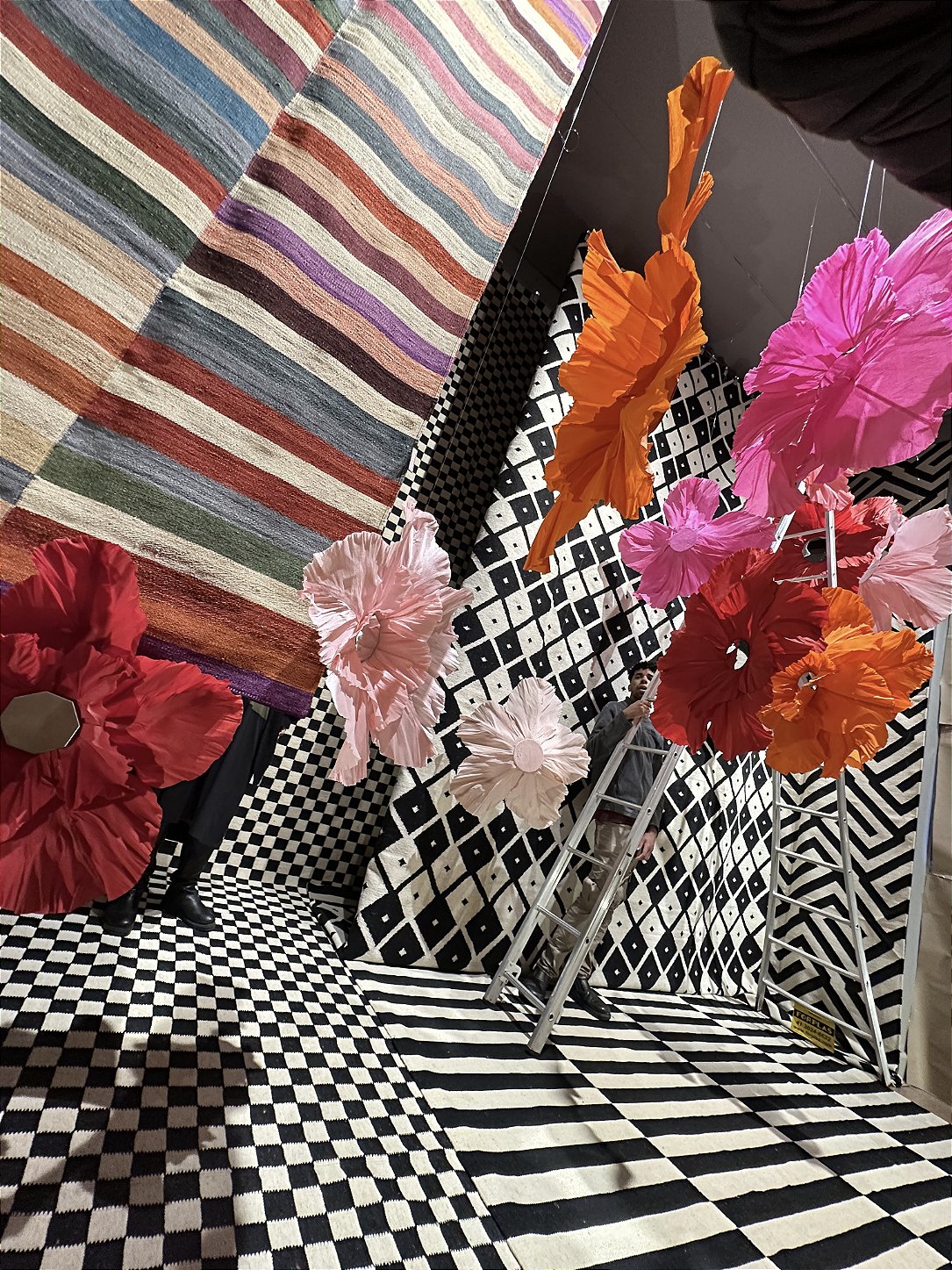 Pedestrians admiring the storefront decorated with suspended giant flowers