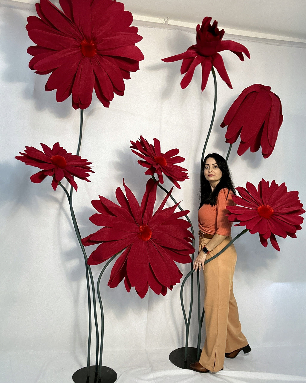 Giant paper daisies on a stand next to designer Jacqueline Benevides, showing the scale